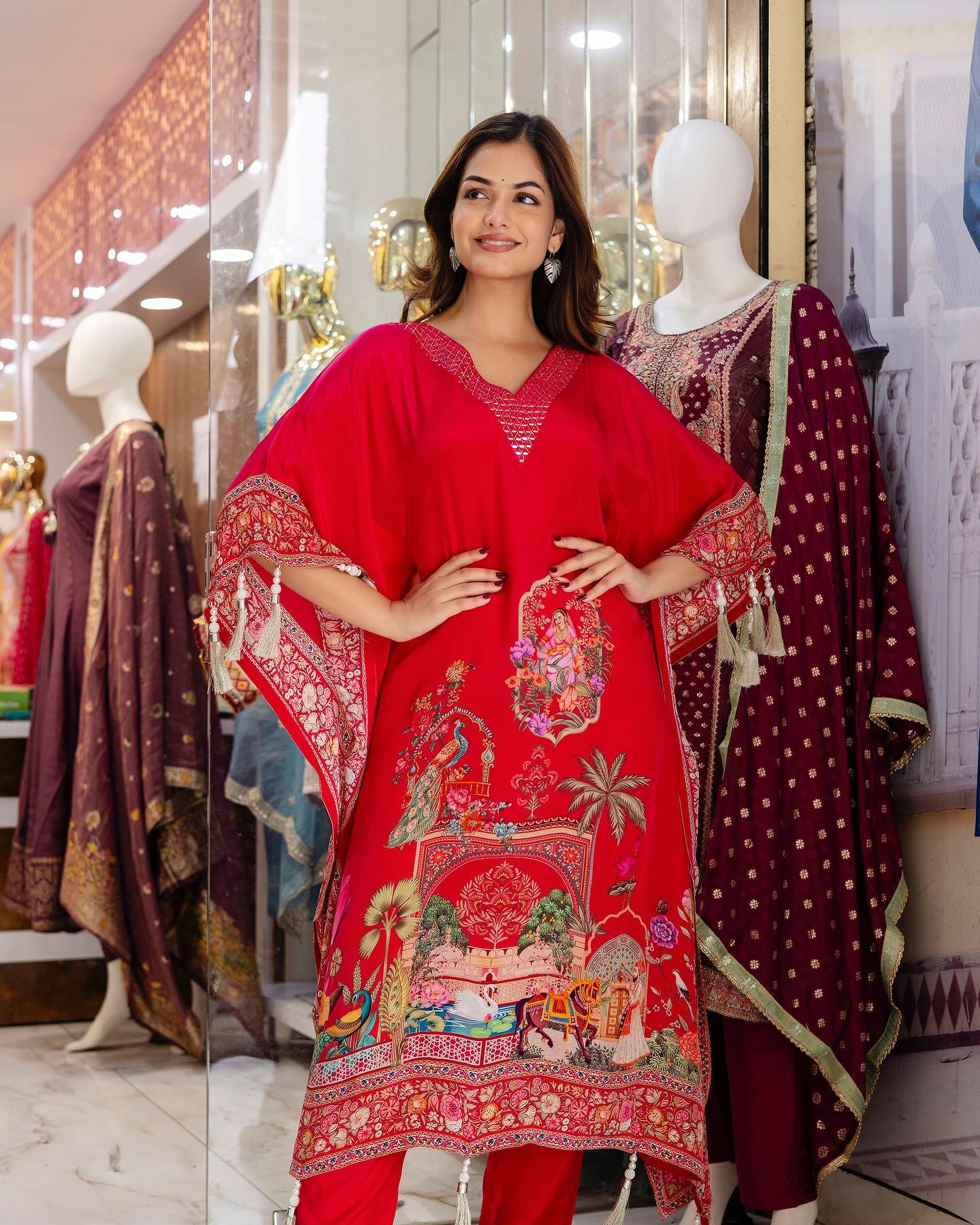 Woman wearing a red embroidered outfit in a store setting with mannequins.