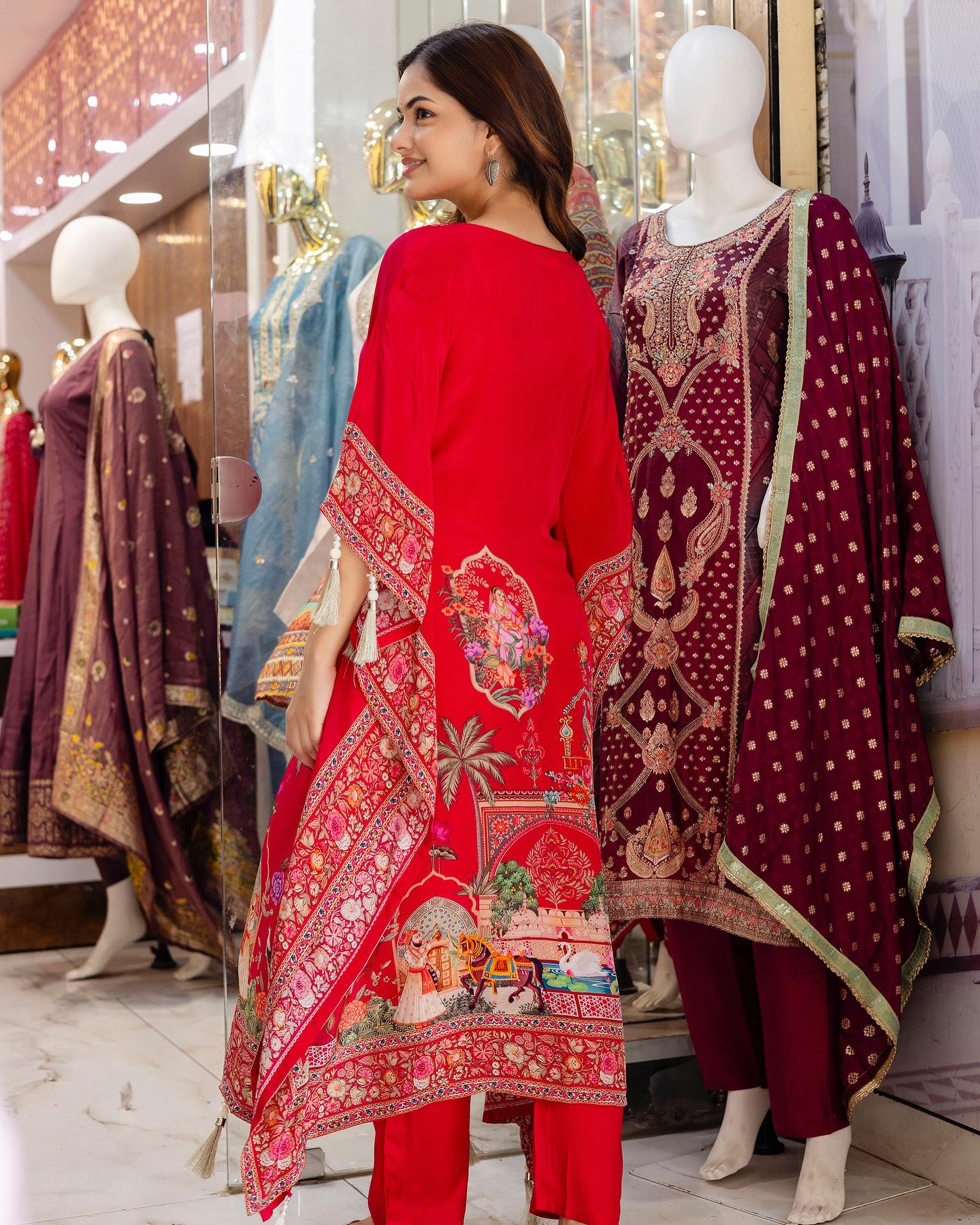 Woman wearing a red traditional outfit with intricate patterns in a store setting.